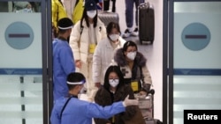 身穿防護服的南韓軍人指引從中國抵達仁川國際機場的乘客進行新冠核酸檢測。（2023年1月4日）