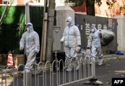 身穿防護服的大白在北京被封控街區行走。 (2022年11月26日)