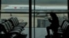 FILE - A passenger checks her phone as an Air China passenger jet taxis past at Beijing Capital International airport, in Beijing, Oct. 29, 2022. China will drop a COVID-19 quarantine requirement for passengers arriving from abroad starting Jan. 8, 2023.