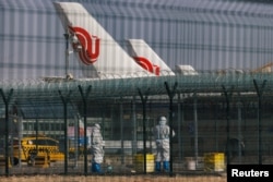 北京國際機場身穿防護服的工作人員站在中國航空公司的飛機附近。（2023年1月6日）