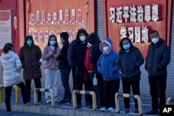 北京市民在宣傳習近平思想的標語牆前排隊等候接受核酸檢測。（2022年12月5日）