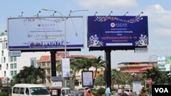 ប្រជាពលរដ្ឋធ្វើដំណើរឆ្លងកាត់ផ្ទាំងបដានៃកិច្ចប្រជុំកំពូលអាស៊ាន នៅត្រង់រង្វង់មូលគល់ស្ពានជ្រោយចង្វា ក្នុងរាជធានីភ្នំពេញ នៅថ្ងៃទី០៧ ខែវិច្ឆិកា ឆ្នាំ២០២២។ (លាស់ លីបលីប/វីអូអេ)