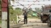 FILE - A Myanmar police officer stands watch as journalists arrive in the village of Shwe Zar, in the northern part of Myanmar's Rakhine state, Sept. 6, 2017.