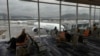 FILE - Travelers wait at a departure area as an aircraft operated by Cathay Pacific Airways taxis at Hong Kong International Airport, in Hong Kong, Oct. 8, 2023.