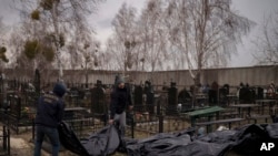 Des corps de personnes retrouvées mortes sont transportés dans un cimetière de Bucha, en périphérie de Kiev, en Ukraine, le 5 avril 2022.