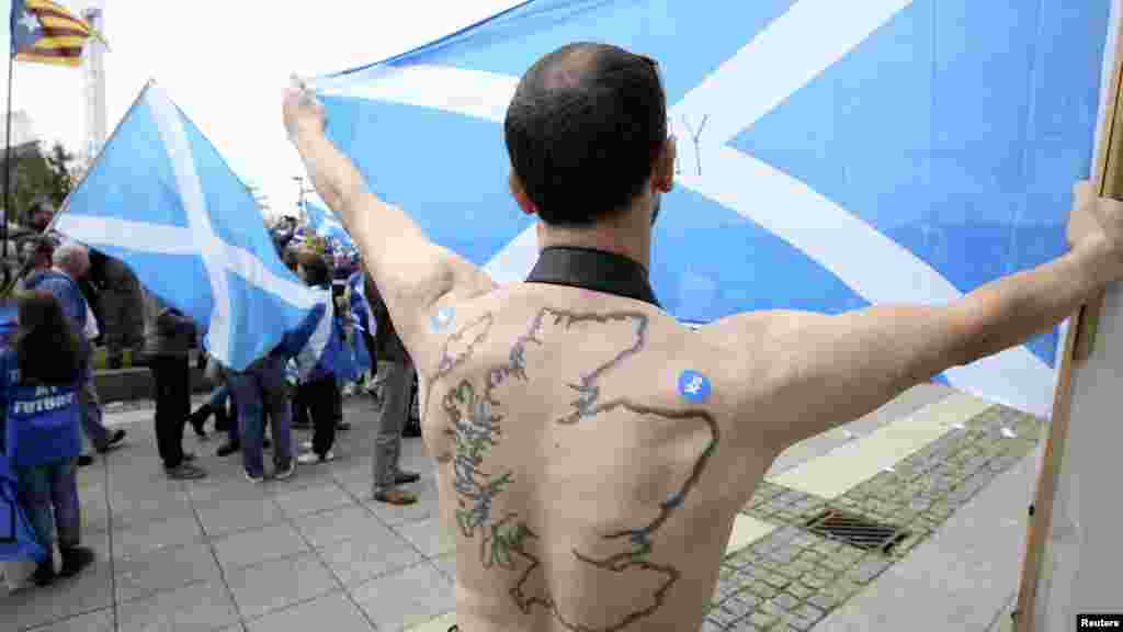A "Yes" supporter with a tattoo of Scotland on his back holds a Saltire flag at a rally outside the BBC in Glasgow, Scotland, Sept. 14, 2014.
