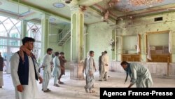 Des Afghans inspectent les dégâts à l'intérieur d'une mosquée chiite à Kandahar le 15 octobre 2021, après un attentat suicide à la bombe lors de la prière du vendredi.