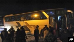 Cette photo publiée par l'agence de presse officielle syrienne SANA, montre les forces gouvernementales syriennes supervisant l'évacuation des bus des combattants rebelles et de leurs familles à Arbeen, dans la région orientale de la Ghouta, près de Damas, le 24 mars 2018.