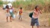 FILE - Displaced people from Myanmar carry donated lunch boxes to their tents along the Thai side of the Moei River in Mae Sot, Thailand on Feb. 5, 2022.