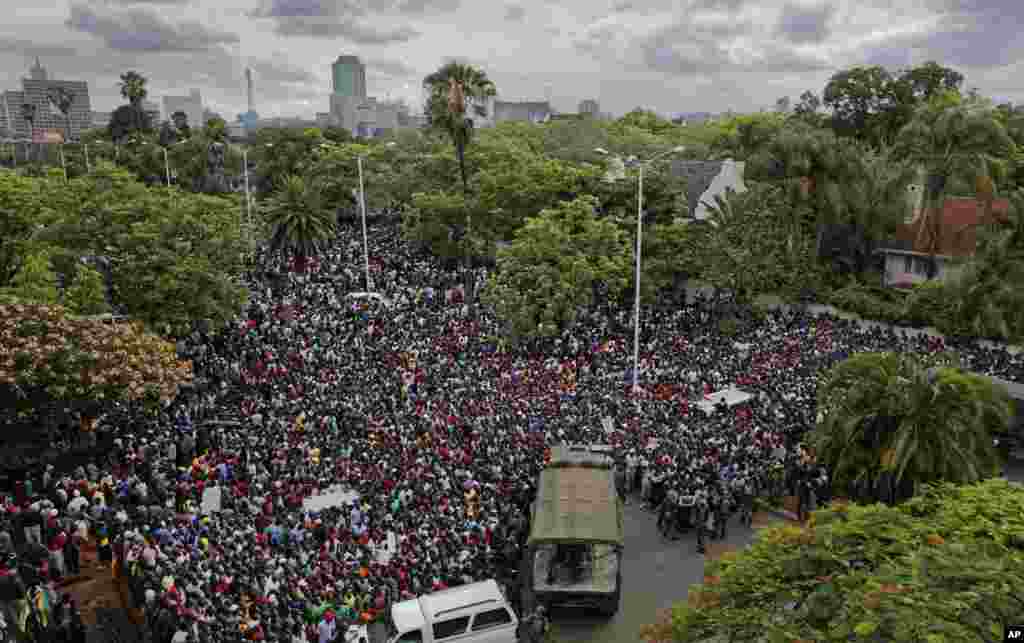 Une foule de manifestants demandant la démission du président Robert Mugabe se réunit derrière un cordon de l'armée sur la route menant à State House à Harare, Zimbabwe, 18 novembre 2017.