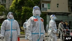 在上海的靜安區，工作人員和自願者正在一座小區內檢查。該小區居民正在家中進行自我檢測。
