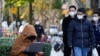 A woman wearing a face mask looks at her laptop on a street, as coronavirus disease (COVID-19) outbreaks continue in Shanghai, China, Dec. 14, 2022.