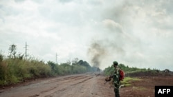 Un Congolais attend le prochain convoi de l'armée se dirigeant vers la ligne de front près de Kibumba dans la zone entourant la ville de Goma au Nord-Kivu, le 25 mai 2022.