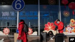 旅客戴著口罩拖著行李來到北京首都機場國際航班出發航站樓入口（2022年12月29日）