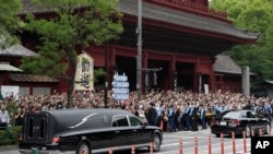 日本前首相安倍晉三的葬禮舉行後，運載安倍棺木的靈車離開寺廟，日本民眾路旁送行。（2022年7月12日）