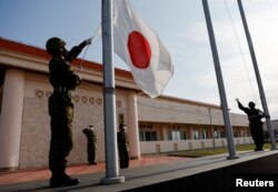 日本沖繩縣宮古島一個軍營裡的自衛隊成員在晚間舉行降旗儀式。（2022年4月20日）