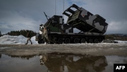 資料照片：在挪威舉行的一次國際軍演期間，一名軍人走過一部M270多管火箭發射系統。 (2022年3月22日)