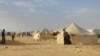 FILE - Syrians walk through the Ruqban refugee camp in Jordan's northeast border with Syria on June 22, 2016. Jordanian authorities announced Tuesday, Nov. 22, 2016, the resumption of aid to thousands of people, half of them children, who have been stuck with little food, water, medical care and other necessities since Jordan closed the border on June 21, 2016, to Syrian refugees. 