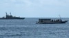 FILE - An Australian Navy boat (L) is positioned near a boat carrying 50 asylum seekers after it arrived at Flying Fish Cove on Christmas Island, about 1615 miles northwest of Perth, Aug. 7, 2011.