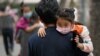 People carrying children wearing face masks to help curb the spread of the coronavirus head to a kindergarten in Beijing on June 9, 2021.