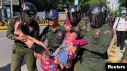 A woman is carried by police officers after security guards broke up a small protest near the Chinese embassy opposing alleged plans to boost Beijing's military presence in the country, in Phnom Penh, Cambodia October 23, 2020. (REUTERS/Heng Mengheang)