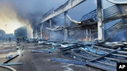 На цьому знімку пожежники працюють над гасінням пожежі в торговому центрі "Амстор", що згорів після ракетного обстрілу в Кременчуці. Україна, понеділок, 27 червня 2022 року. (Державна служба України з надзвичайних ситуацій через AP)