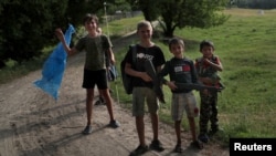 烏克蘭少年兒童在哈爾科夫地區的一處烏克蘭國土防衛軍訓練場地附近嬉戲。(2022年6月17日)