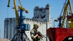 2022年6月12日，一名俄羅斯軍人在馬里烏波爾海港一個碼頭上站崗。背景中有穀倉。
