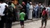 Rebel fighters stand guard as people queue for bread in the rebel held al-Shaar neighborhood of Aleppo, Syria July 14, 2016. 