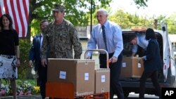 美國副總統邁克·彭斯(Mike Pence)在維吉尼亞州亞歷山大市的伍德賓康復和醫療中心(Woodbine Recovery And Healthcare Center)移動一輛手推車，車裡裝著來自聯邦應急管理局(FEMA)的一箱箱個人防護用品。 （2020年5月7日）