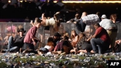 People scramble for shelter at the Route 91 Harvest country music festival after apparent gun fire was heard on October 1, 2017 in Las Vegas, Nevada.