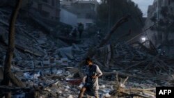 EDITORS NOTE: Graphic content / TOPSHOT - A man walks atop the rubble of a tower destroyed in an Israeli air stike in Gaza City on October 7, 2023.