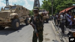 Afisa wa polisi wa Kenya anayeshiriki katika kikosi cha kimataifa akiwataka waandishi wa habari kusimama kando mjini Port-au-Prince nchini Haiti, Julai 17, 2024. Picha ya AP