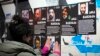 A woman hangs portraits of activists injured during protests against the government's decision to suspend negotiations on joining the European Union in Tbilisi, Georgia, on Dec. 7, 2024.