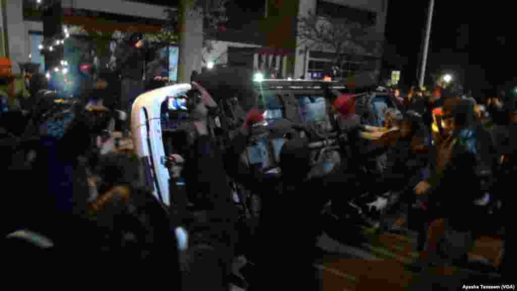 Au cours d'une deuxième nuit de violences à la suite de la décision d'un grand jury de ne pas inculper un policier blanc dans la mort par balle d'un adolescent noir, les manifestants attaquent et renversent une voiture de police à l'extérieur Ferguson City Hall, à Ferguson, Missouri, le 25 novembre 2014 .