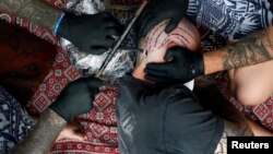 Un homme tatoué par Brent McCown (G) lors de la neuvième convention sur le tatouage à Londres, le 27 septembre 2013.