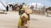 FILE - A girl carries empty plastic containers at a camp Maiduguri, Nigeria, Aug. 28, 2016.