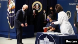 President Joe Biden watches as Linda Bussey receives the first round of the COVID-19 vaccine during an event to commemorate the 50 millionth vaccination at the White House, Feb. 25, 2021.