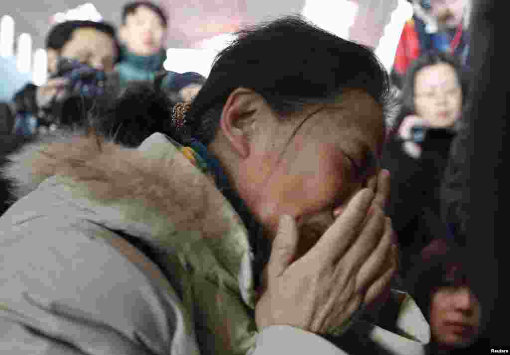 A relative of a passenger onboard Malaysia Airlines flight MH370 cries, surrounded by journalists, at the Beijing Capital International Airport in Beijing, China.