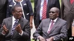 L'ex-vice-président Emmerson Mnangagwa, à gauche, discutant avec le président Mugabé lors d'une cérémonie à Harare le 12 décembre 2014 (AP Photo/Tsvangirayi Mukwazhi)