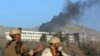 Afghan security personnel stand guard as black smoke rises from the Intercontinental Hotel, Jan. 21, 2018, after an attack in Kabul, Afghanistan. Gunmen stormed the hotel and set off a 12-hour gun battle with security forces that continued into Sunday morning, as frantic guests tried to escape from fourth- and fifth-floor windows.