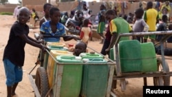 Des enfants déplacés qui ont fui leurs villages du nord du Burkina Faso, à la suite d'attaques d'agresseurs, poussent des charrettes chargées d'eau dans une école de Ouagadougou, Burkina Faso, le 15 juin 2019.