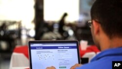 A man demonstrates how he enters his Facebook page as he works on his computer at a restaurant in Brasilia, Brazil, Thursday, Jan. 4, 2018.