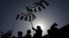 FILE - Supporters of the Jamaat-ud-Dawa Islamic organization are silhouetted against the sun as they raise their party flags while taking part in an anti-American rally in Lahore, May 25, 2012. 