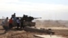 FILE - Fighters are seen firing a vehicle-mounted weapon on the outskirts of Sidra, Libya. The report describes unlawful killings, including executions of people taken captive. 
