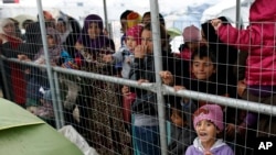 Des migrants attendent de la nourriture dans le camp de réfugiés de fortune de Idomeni, en Grèce, le 23 mars 2016.