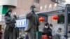 资料照片：在中国武汉市，一名女子正走过带着口罩的雕塑面前。世卫组织新冠溯源专家小组当时正在武汉考察。（2021年1月29日）