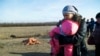 FILE - A woman with her child and others pass body of a man, who died in a land mine explosion near a frontline crossing to Ukrainian government-controlled territory, in the war conflict-hit Donetsk region, near Donetsk, eastern Ukraine, Feb. 10, 2015. The U.N. children’s fund calls on Feb. 21, 2016, the daily suffering endured by more than one-half million Ukrainian children victimized by two years of conflict intolerable. 