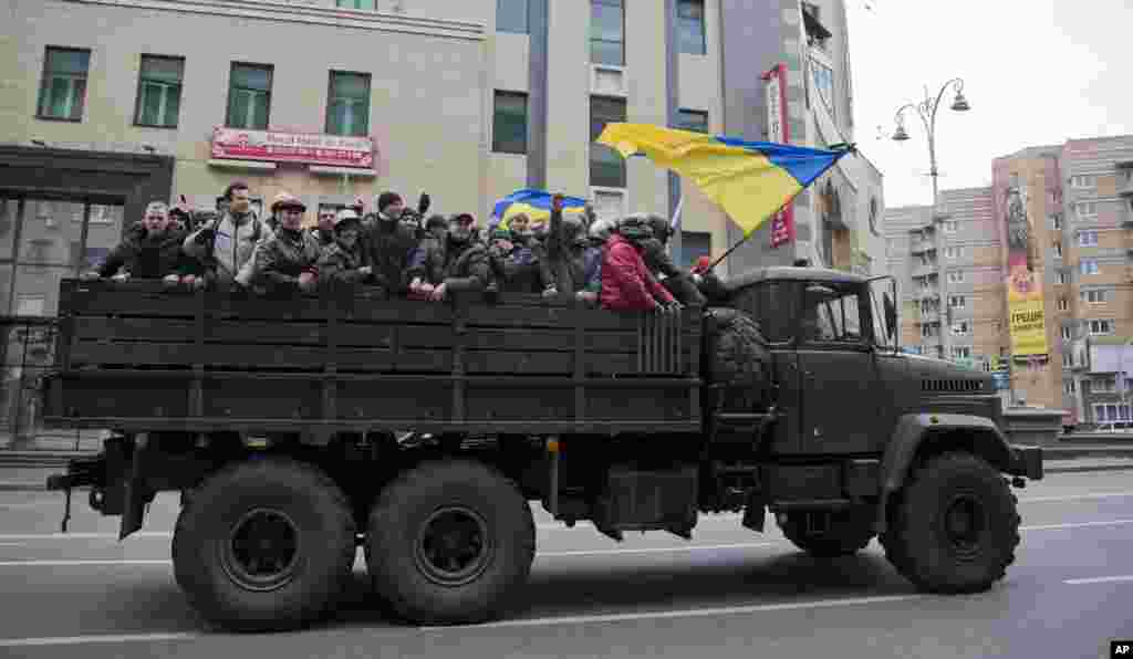 Protesters ride atop of what appears to be a military truck, in central Kyiv.
