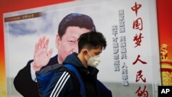 北京街道上，戴口罩的行人走過帶有中國領導人習近平像的海報，海報上有標語“中國夢人民的夢”（2017年10月26日）